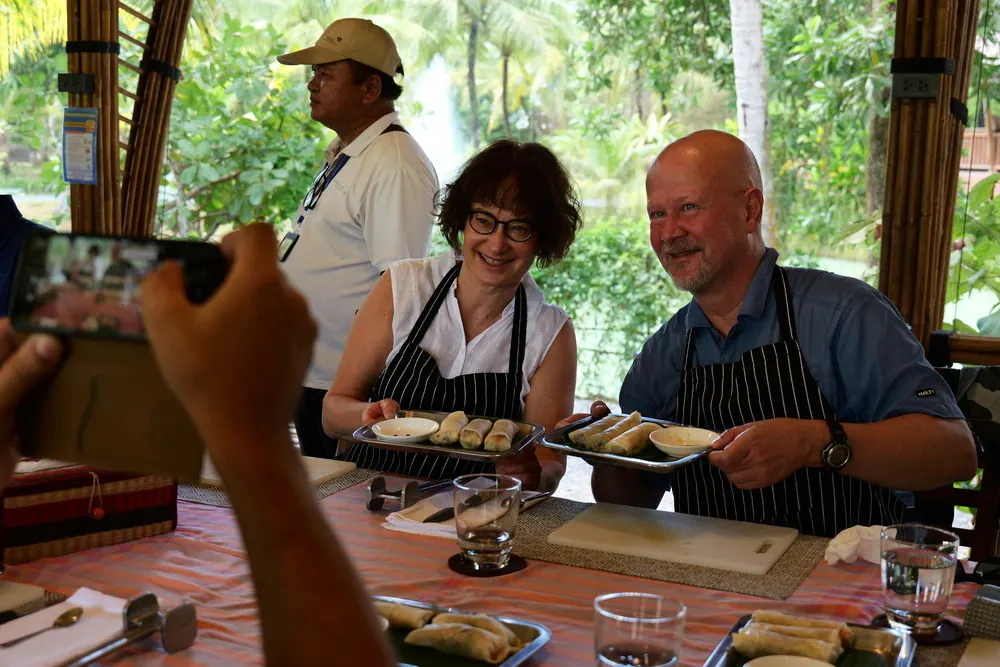 Share Your Culinary Creations Two cooking class visitors holding plates of spring rolls they prepared