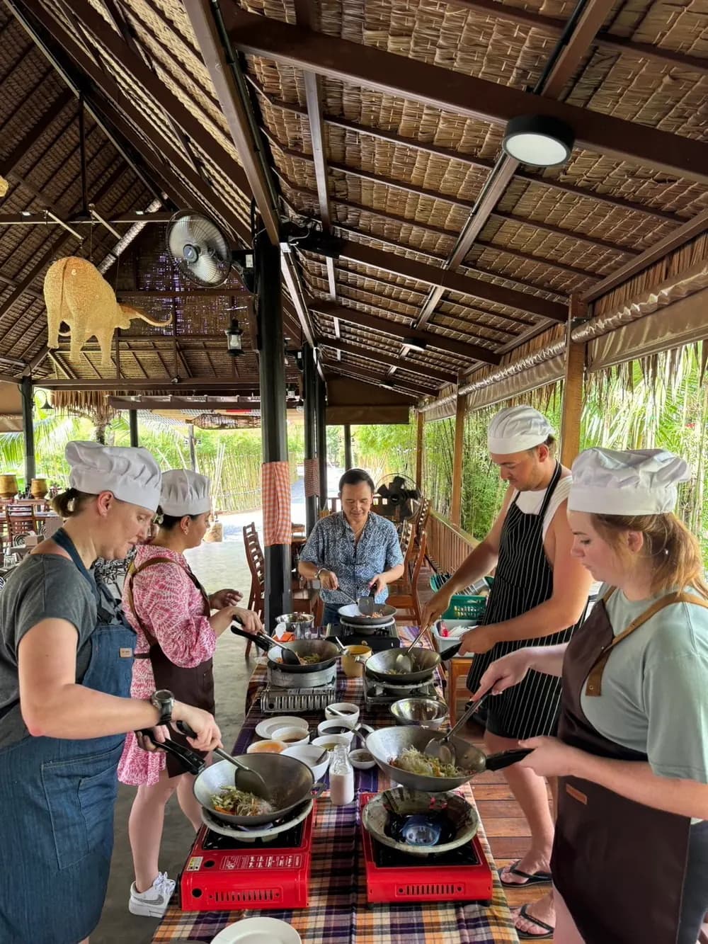 Fresh Cooking Experience A group of visitors cooking at individual woks under a thatched roof